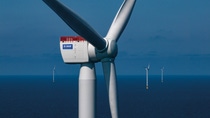 Close-up of a large wind turbine against a deep blue sea backdrop. Other turbines dot the horizon. Close-up of a large wind turbine against a deep blue sea backdrop. Other turbines dot the horizon.